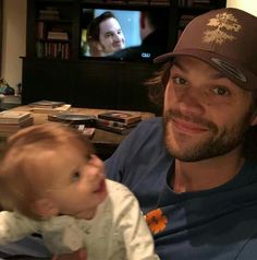 a man holding a baby in front of a tv