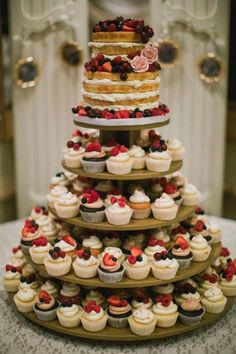 a tiered cake with cupcakes and berries on it