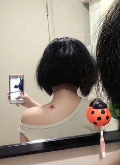 a woman taking a selfie in front of a mirror with her hair styled like a ladybug