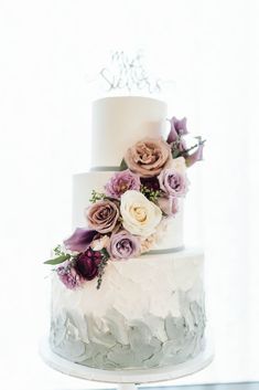 a three tiered wedding cake with flowers on top