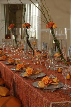 a long table is set with orange flowers and place settings for an elegant dinner party