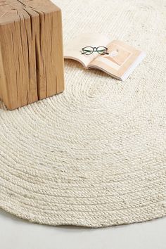 a wooden block sitting on top of a rug next to a book and eyeglasses