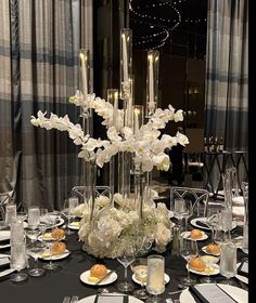 an elegant centerpiece with white flowers and candles is displayed on a black table cloth