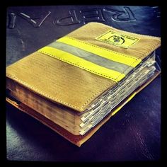 an old book with yellow and grey stripes is sitting on a leather tablecloth covered surface