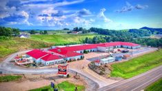 an aerial view of a red roofed building in the middle of a rural country road