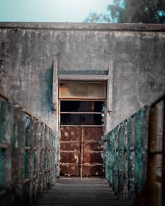 an old door is open on the side of a building that has rusted metal railings