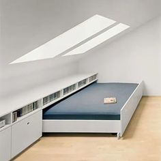 a bed sitting under a window next to a white cupboards and drawers in a room