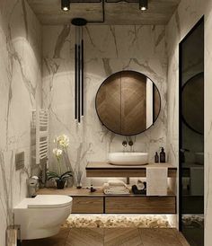 a bathroom with marble walls and flooring is pictured in this image, it has a round mirror on the wall