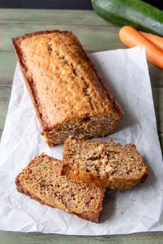 sliced loaf of banana bread sitting on top of a piece of paper next to carrots and zucchini