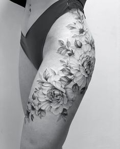 black and white photo of a woman's thigh with flowers on the lower leg