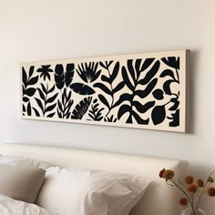 a white bed topped with pillows next to a painting