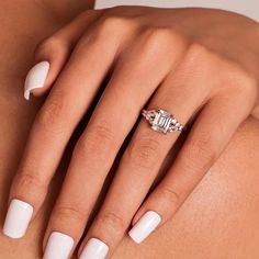 a woman's hand with white manicured nails and an engagement ring on her finger