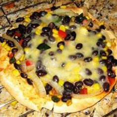 an uncooked pizza with black olives, corn and peppers on it sitting on a counter