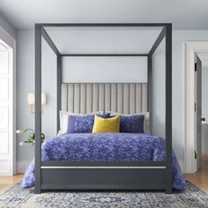 a bedroom with a four poster bed, blue and yellow pillows and rugs on the floor