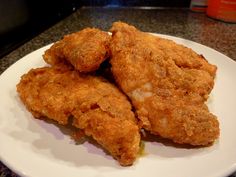 a white plate topped with fried chicken on top of a counter