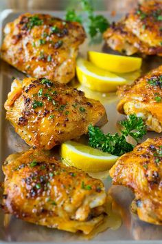 chicken thighs with lemons and parsley on a baking sheet