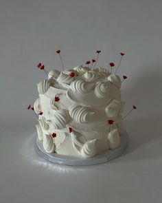 a white cake with red flowers on top is sitting on a platter and looks like it has been made out of fondant