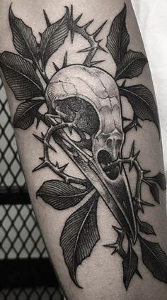 a black and white photo of a skull with leaves on it's thigh,