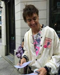 a young man in a white jacket is holding some papers and smiling at the camera