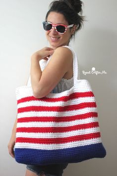 a woman wearing sunglasses holding a red, white and blue crocheted tote