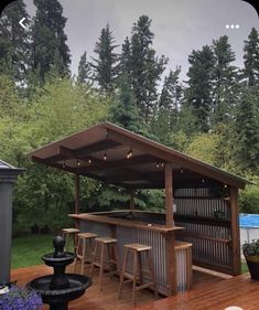 an outdoor bar with stools and tables on a deck in front of some trees