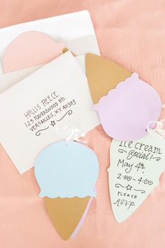 three ice cream cones are on top of a pink tablecloth with two envelopes