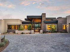 a modern house with large windows and brick driveway