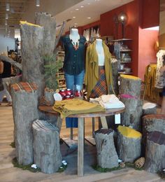 mannequins are displayed in front of wooden stumps and other clothing on display