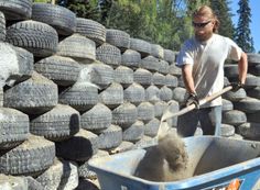 a man is shoveling sand into a wheelbarrow filled with tires and gravel