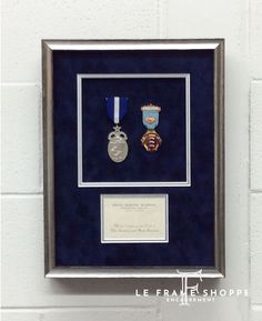 two medals are in a shadow box on the wall