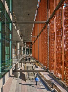 people are walking down the walkway in front of an office building with wooden slats