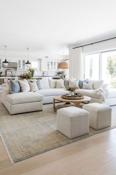 a living room filled with white furniture and lots of pillows on top of the couches