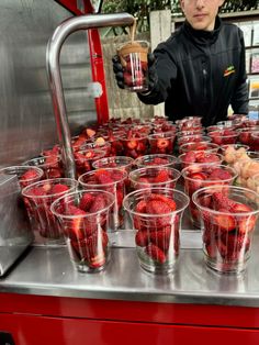 a man is filling cups with strawberries