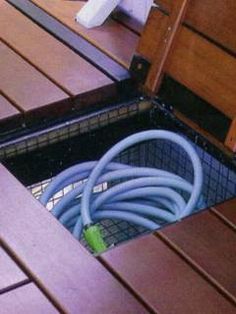 the inside of an open suitcase with hoses in it on a wooden decking area