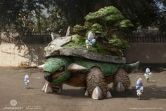 a large turtle statue sitting in the middle of a parking lot next to a tree