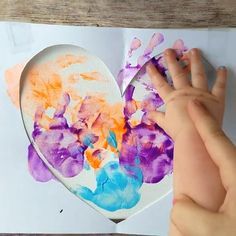 a child's hand is touching a heart shaped painting