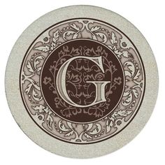 the letter g in an ornate design on a white plate with brown and tan accents