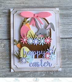 a happy easter card with an egg and bunny in a basket on the side, surrounded by flowers