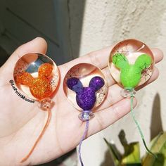 three handmade glass ornaments in the shape of birds on top of each other, one being held by a person's hand