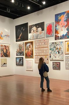 a woman standing in front of a wall with pictures on it