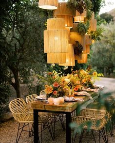 an outdoor dining area with wicker chairs and wooden table surrounded by greenery hanging from the ceiling