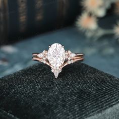 an engagement ring with three stones on top and two bands around the band, sitting on a black velvet box