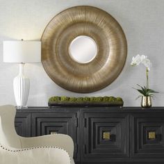 a white chair sitting in front of a mirror on top of a wooden dresser next to a lamp