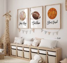 a baby's room with three framed sports pictures on the wall and two stuffed giraffes