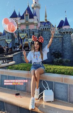 a woman sitting on the steps in front of a castle with balloons and streamers