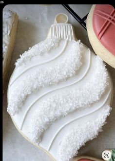 a cookie decorated with icing and white frosting on top of a table next to cookies