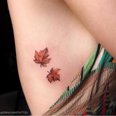 two small leaves on the back of a woman's left arm, one is orange and the other is red