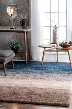 a living room area with a rug, chair and table in front of a window