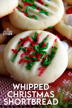 some cookies with sprinkles are on a red and white table cloth next to christmas decorations