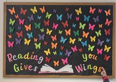 a child pointing at a bulletin board with butterflies on it that reads reading gives wings